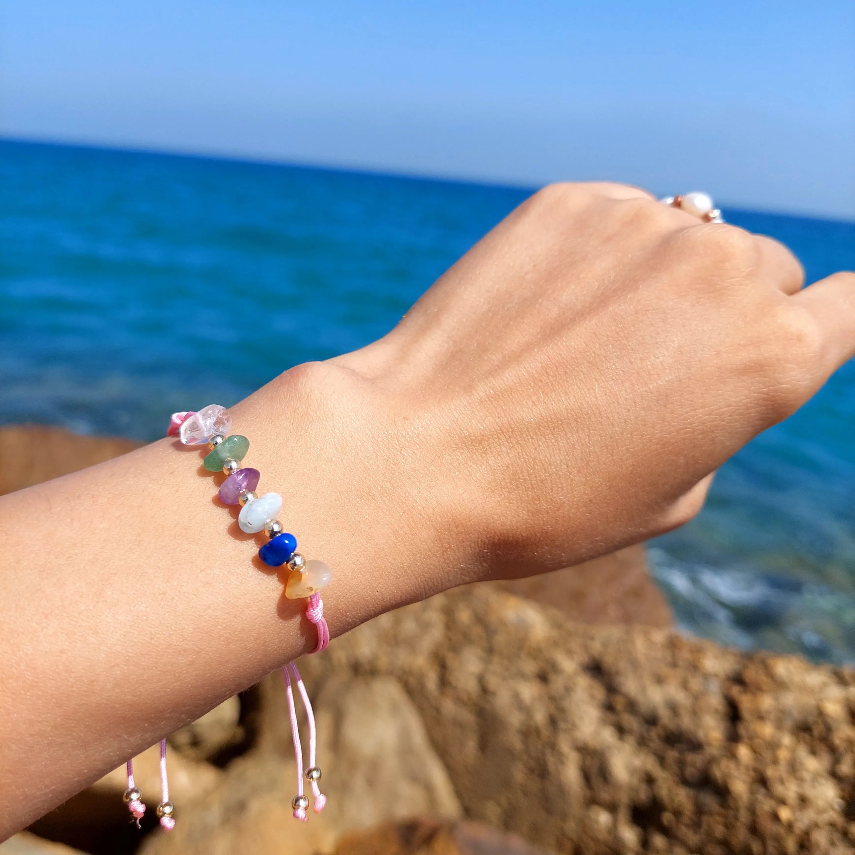Colorful beaded bracelet on a wrist with a blue ocean background