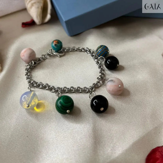 Bracelet with colorful charms on a textured surface with a blue box in the background