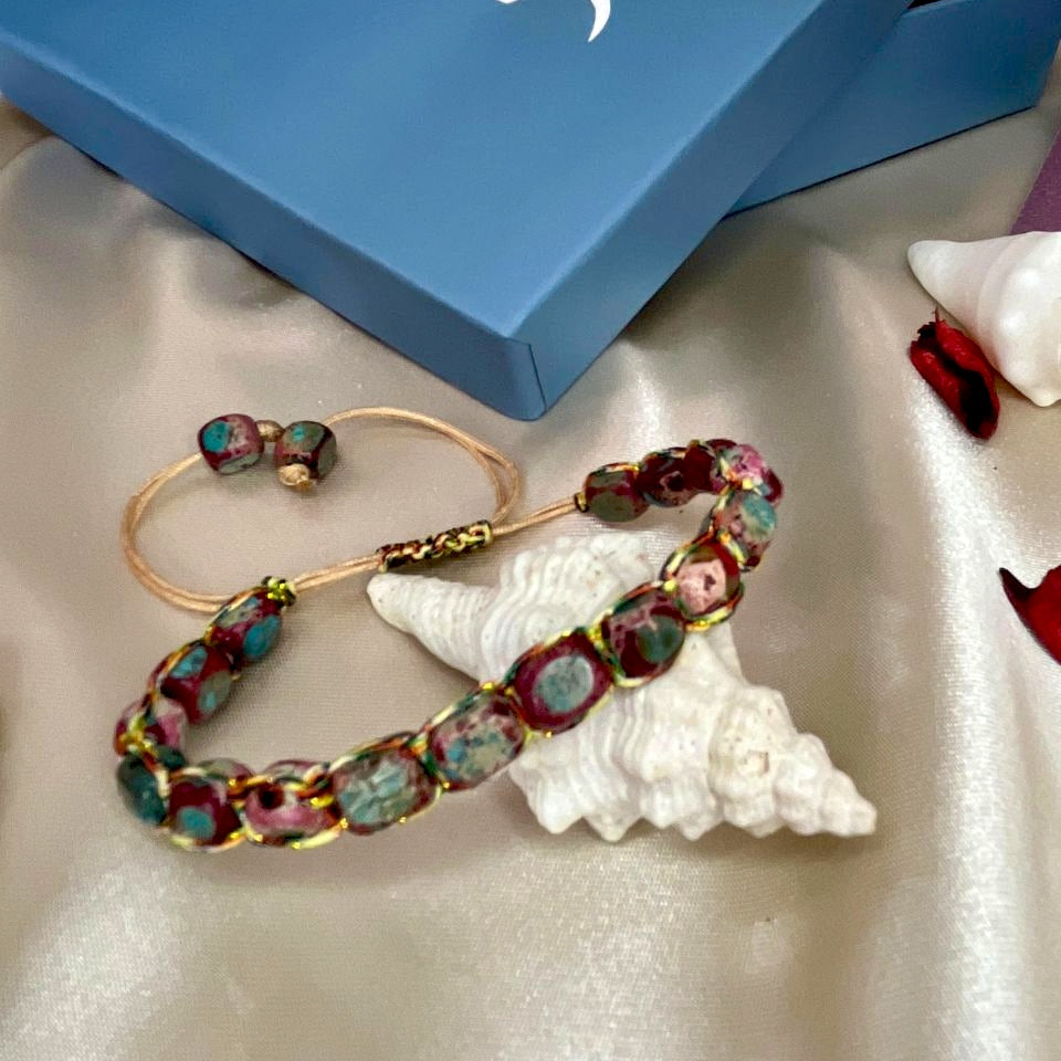 Colorful beaded bracelet on a white shell with a blue box labeled 'GAIK' in the background.