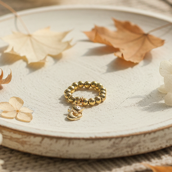 Gold bracelet on a textured surface with dried leaves and flowers