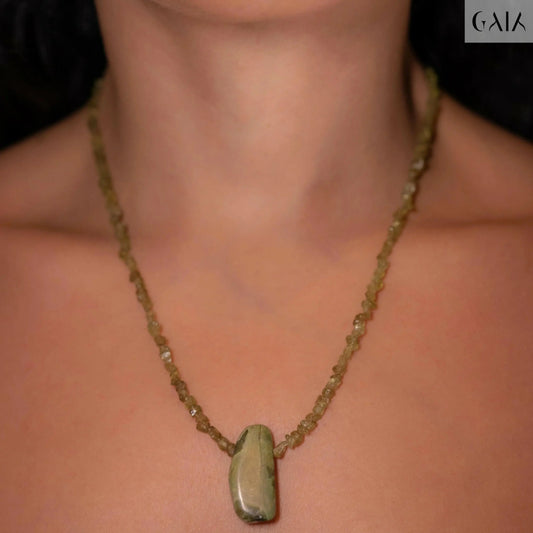 Close-up of a semi-long Hope Necklace featuring green Peridot beads and a natural Tourmaline centerpiece on a neck.