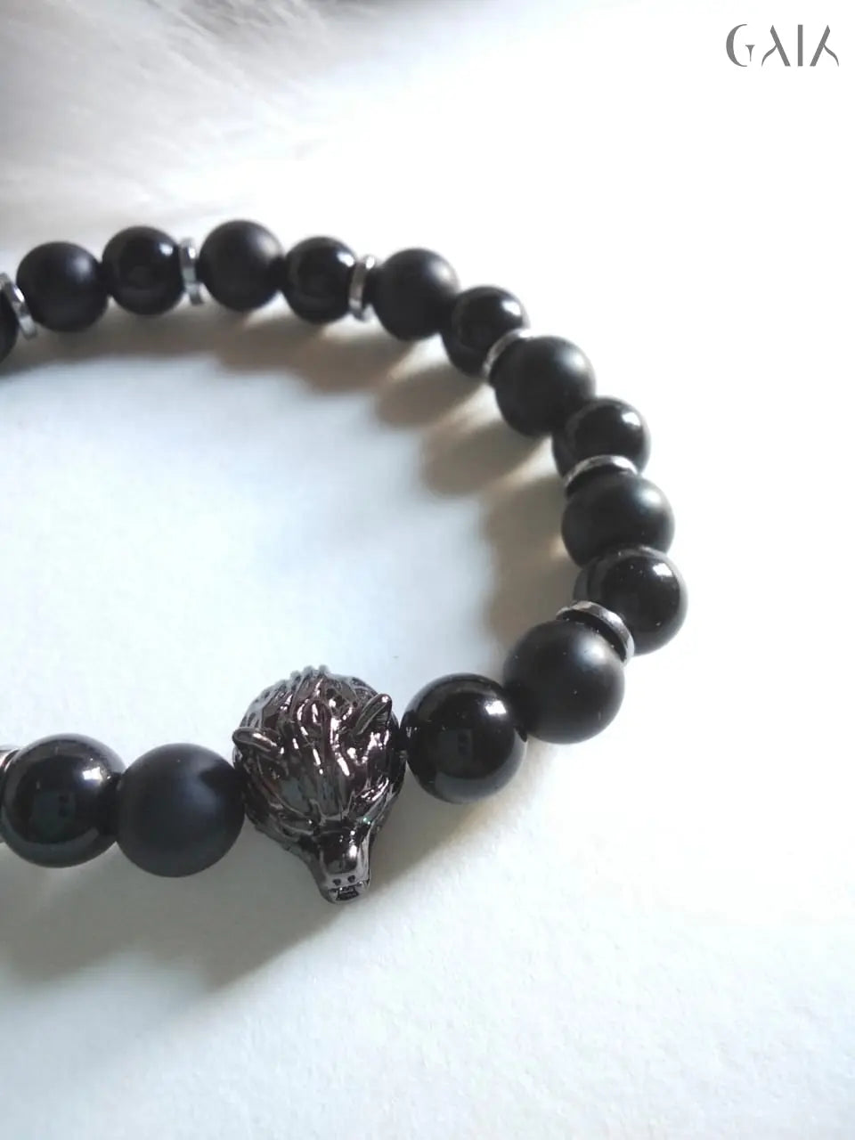 Black beaded bracelet with a lion head charm on a white background