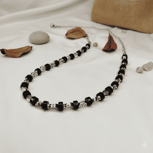 Necklace with black and silver beads on a white fabric background