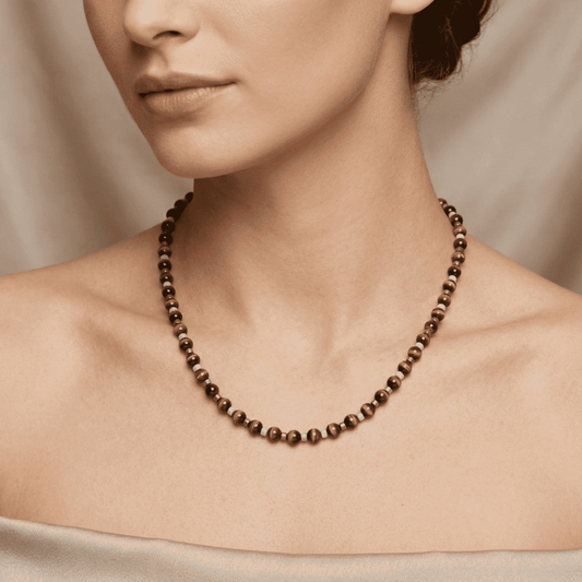 Necklace with brown beads worn by a person against a neutral background