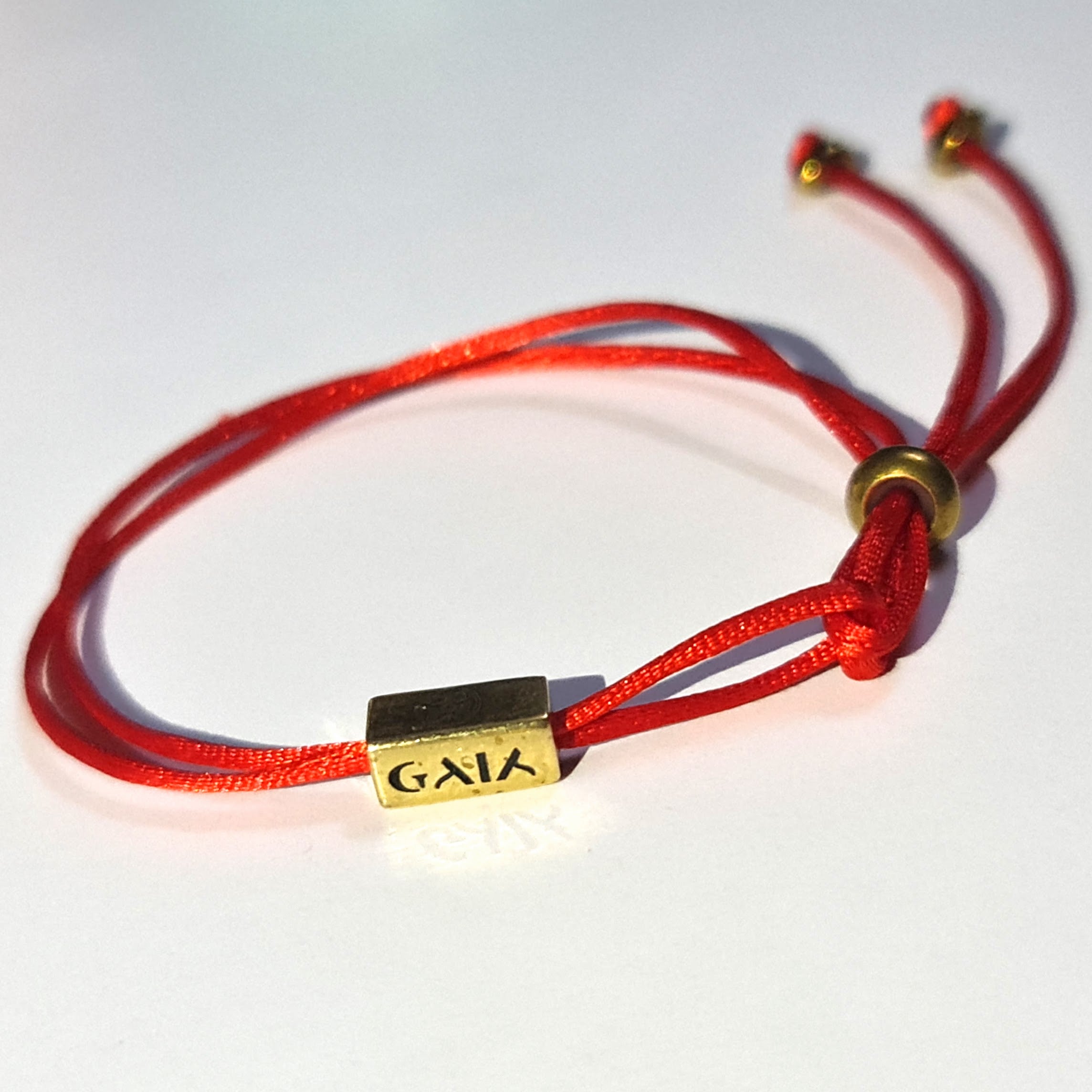 Red bracelet with a gold tag labeled 'GAIA' on a white background
