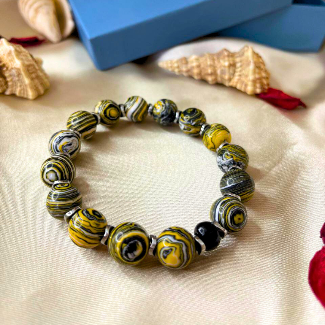 Beaded bracelet with yellow and black pattern on a beige surface, with a blue box labeled 'Cala' in the background.