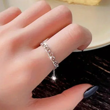 Hand wearing a silver ring with a slice of cheesecake on a plate in the background