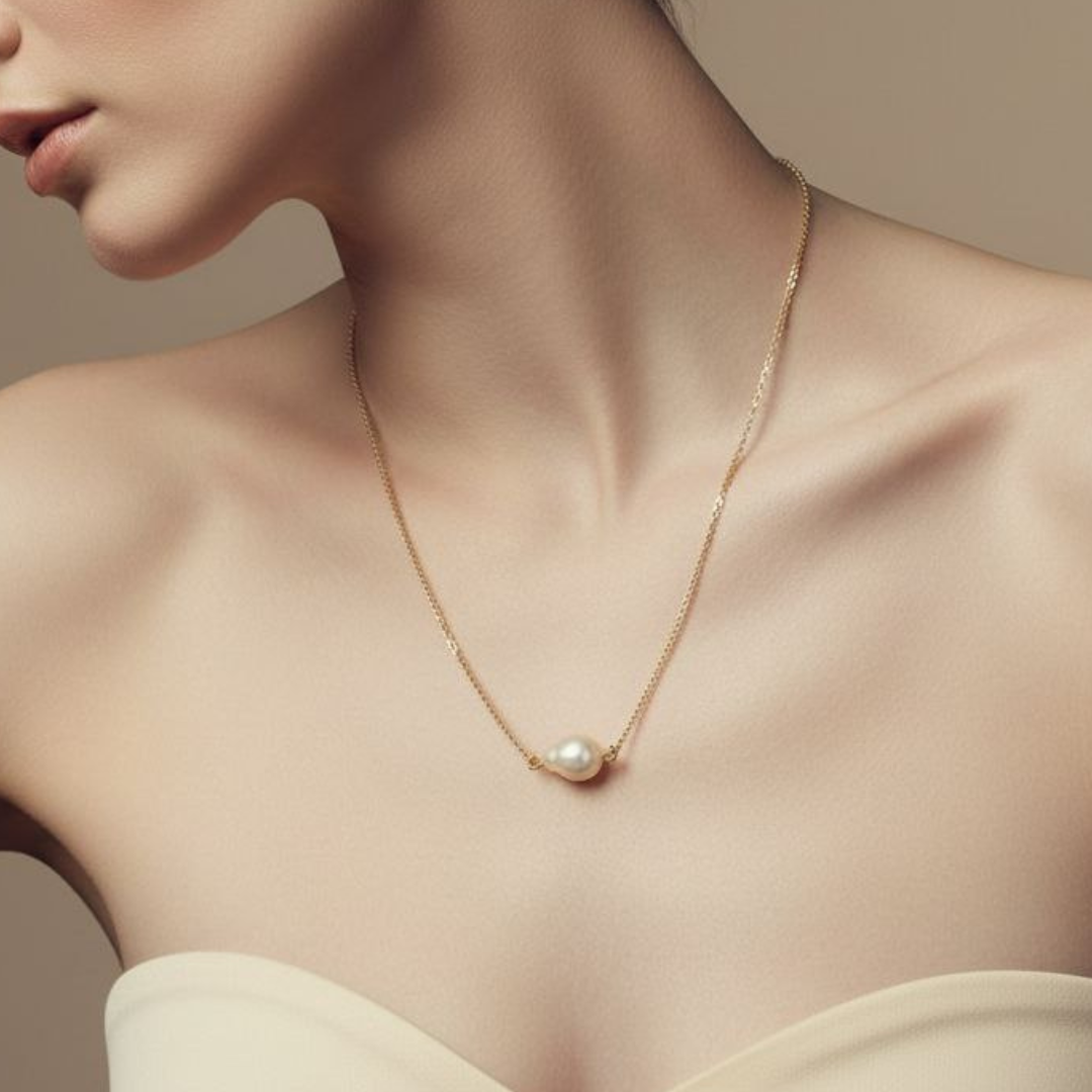 Gold necklace with a pearl pendant worn by a model against a neutral background