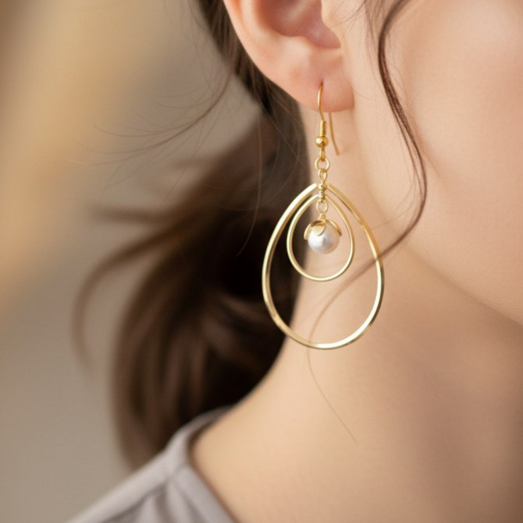 Close-up of a gold earring with a pearl drop worn by a person.