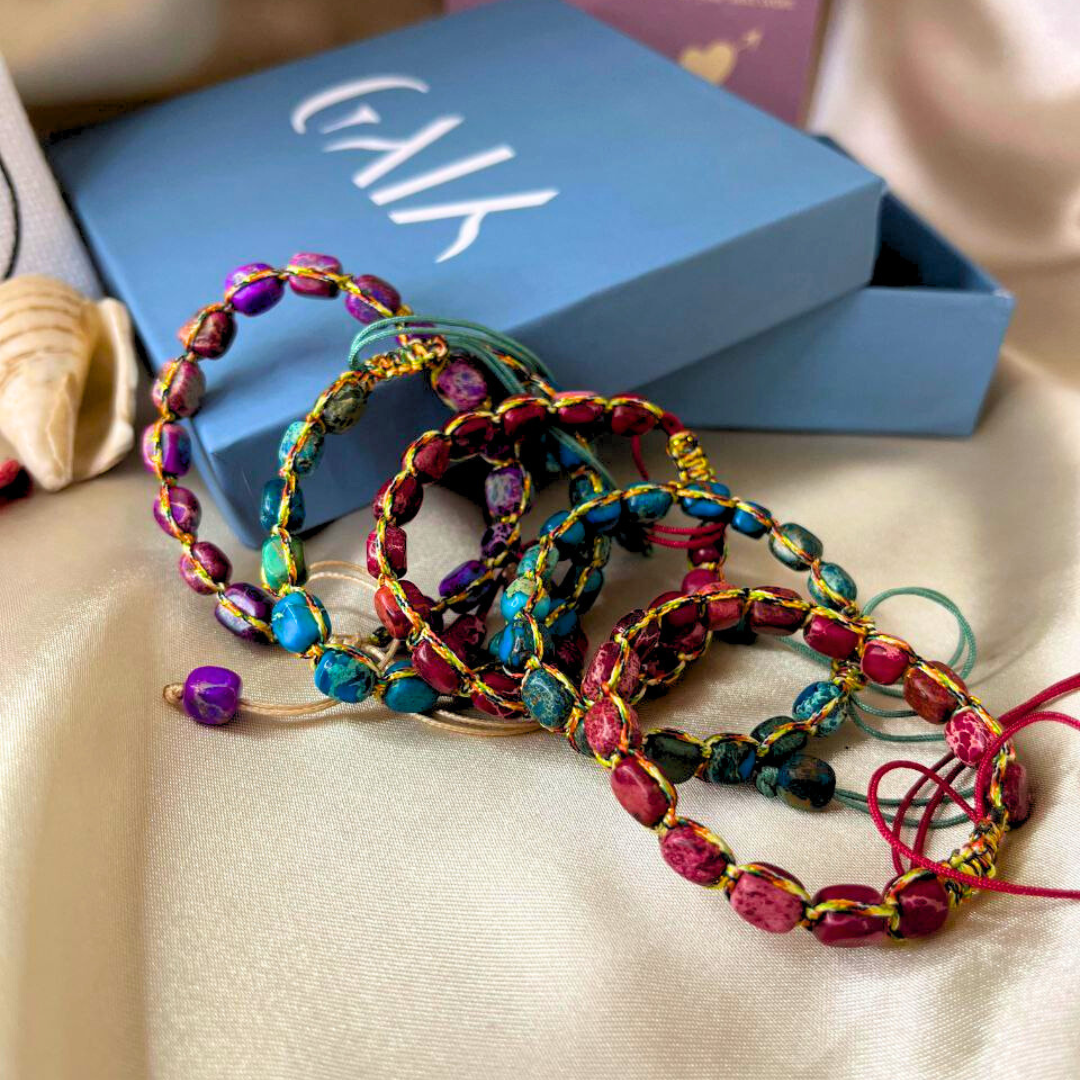 Colorful beaded bracelets on a beige surface with a blue box in the background.