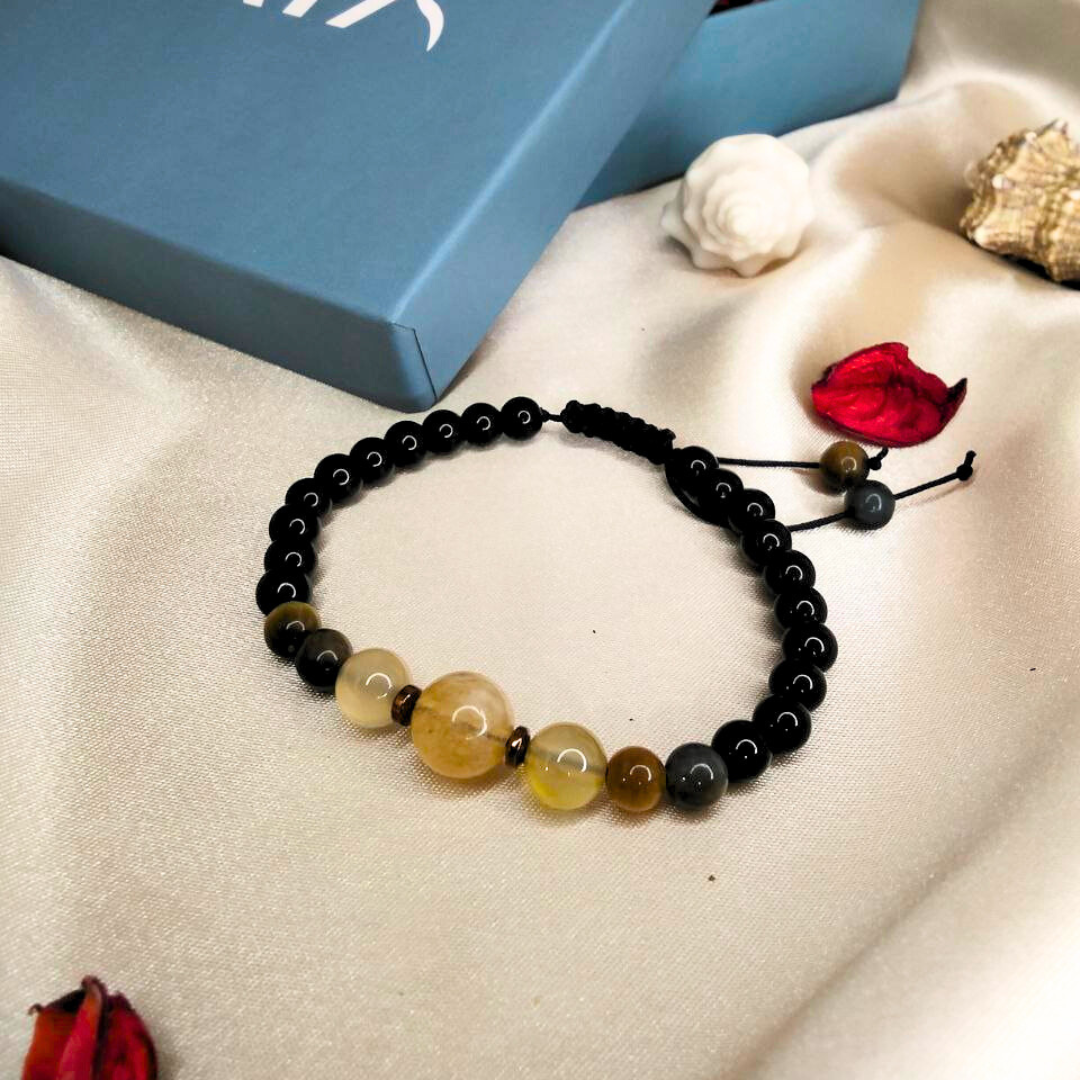Black beaded bracelet on a beige surface with a blue box labeled 'GAIA' in the background.