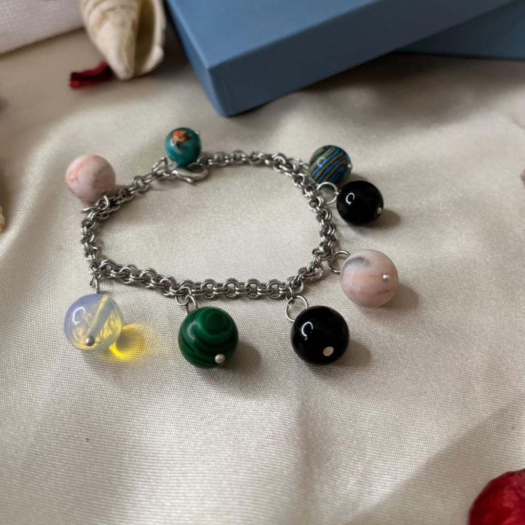 Bracelet with colorful charms on a textured surface with a blue box in the background