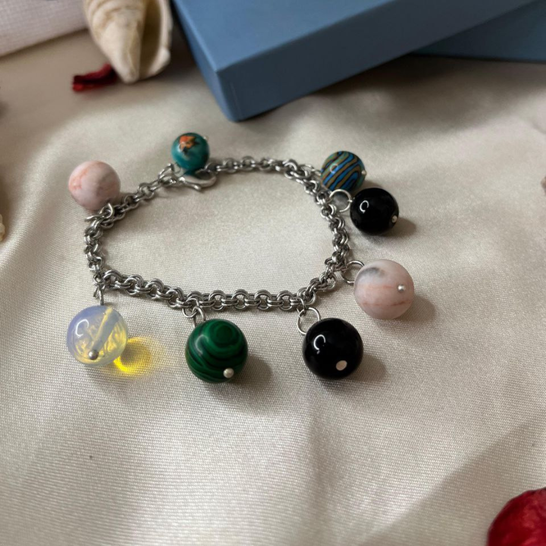 Bracelet with colorful charms on a textured surface with a blue box in the background