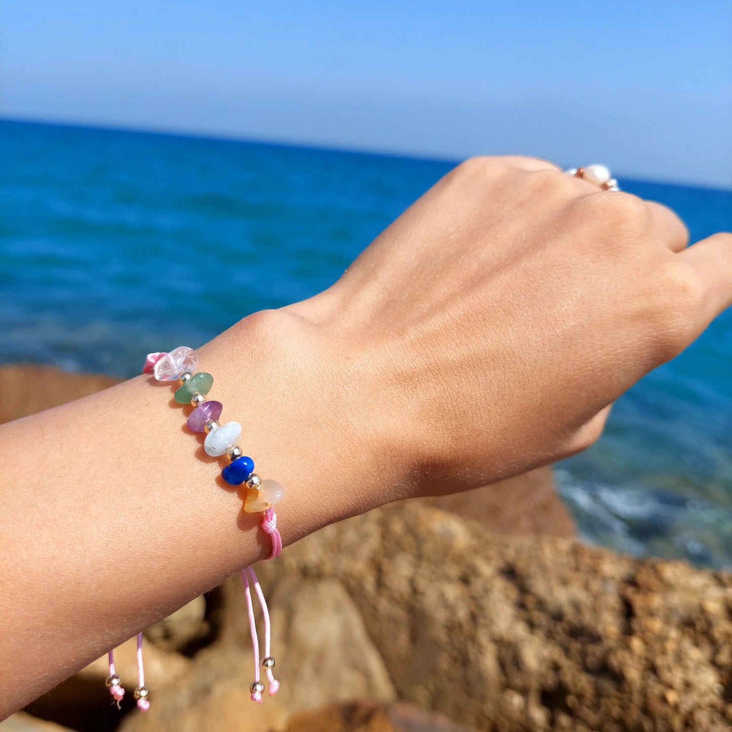 Colorful beaded bracelet on a wrist with a blue ocean background