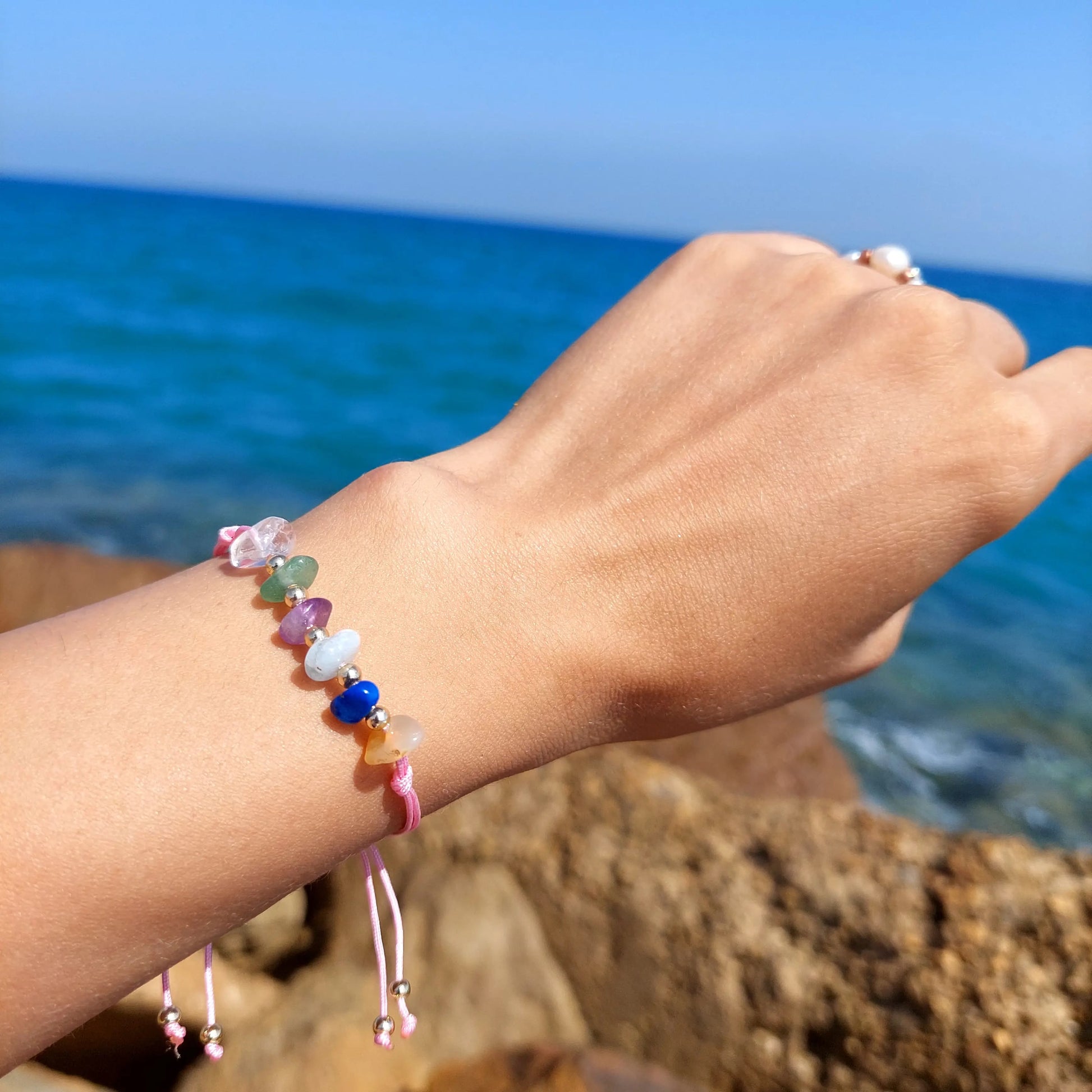 Colorful beaded bracelet on a wrist with a blue ocean background