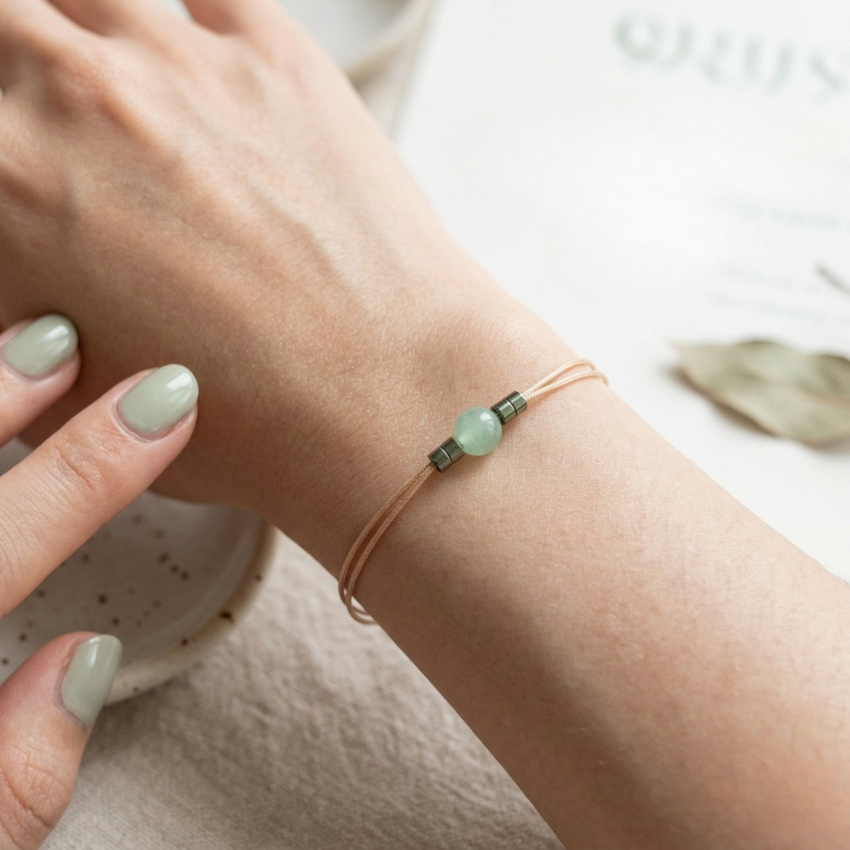 Close-up of a wrist wearing a bracelet with green beads on a light background