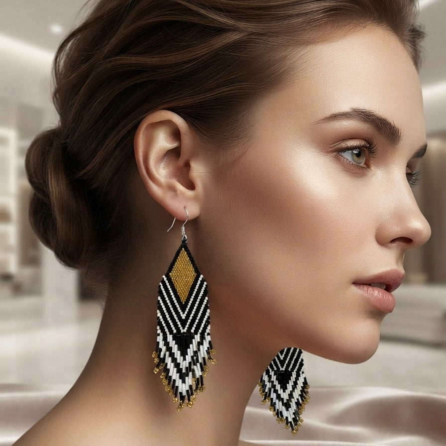 Woman wearing long black, white and gold beaded geometric drop earrings.
