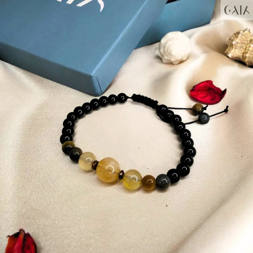 Black beaded bracelet on a beige surface with a blue box labeled 'GAIA' in the background.