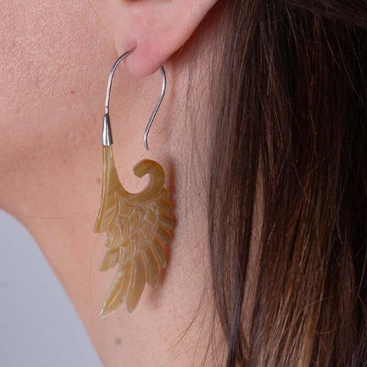 Close-up of handcrafted Gaia's Silver Wings Earrings made from natural seashells worn on ear