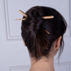 Dark brown hair styled in a bun secured with a hand-carved olive wood hair stick with a smooth finish