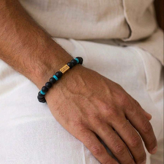 Close-up of a wrist wearing a black and blue beaded bracelet with a visible brand name.