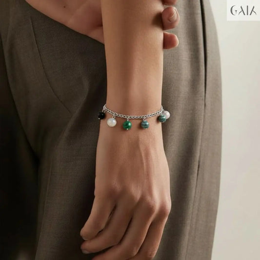 Person wearing a brown jacket with a white shirt and a bracelet on a neutral background