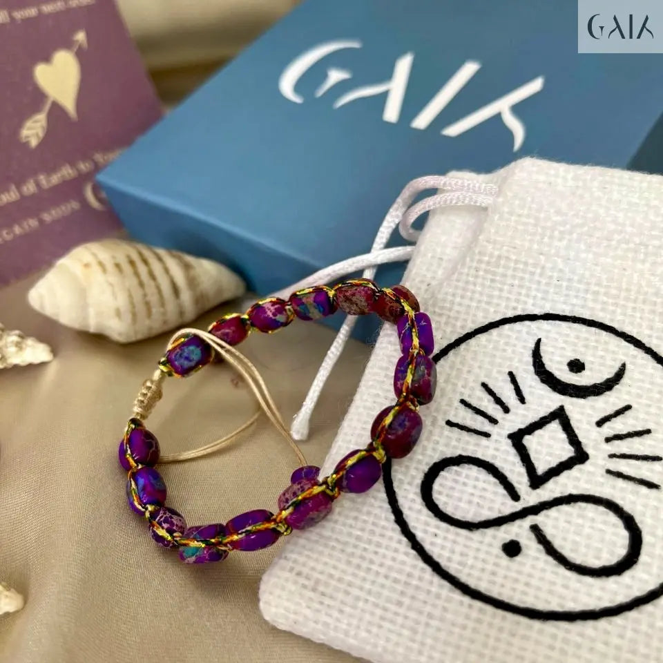 Beaded earrings on a white drawstring bag with a logo, next to a blue box and book.