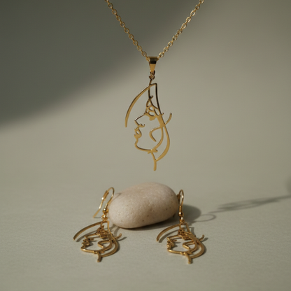 Gold necklace and earrings with a stone on a neutral background