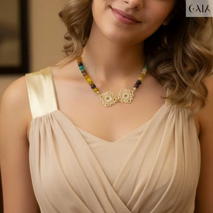 Woman wearing a necklace with a beige dress against a neutral background
