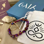 Beaded earrings on a white drawstring bag with a logo, next to a blue box and book.