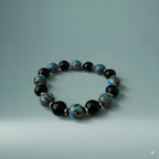 Beaded bracelet with black, blue, and silver beads on a light gray background