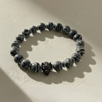 Black and white beaded bracelet on a beige background with 'GAIA' branding.