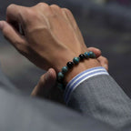 Hand wearing a beaded bracelet with a blurred background
