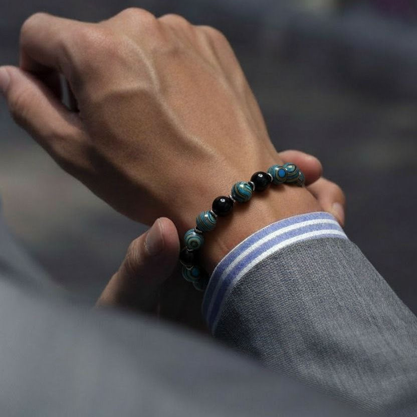 Hand wearing a beaded bracelet with a blurred background
