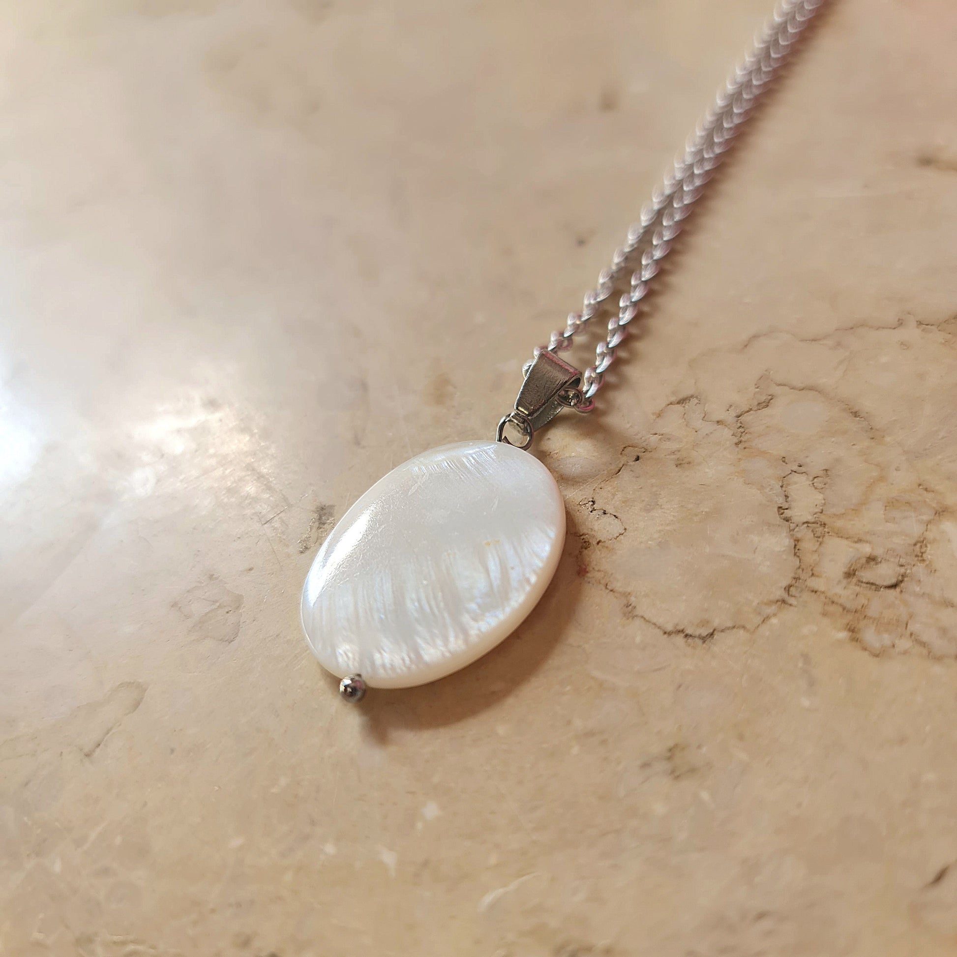 Necklace with a large shell pendant on a marble surface