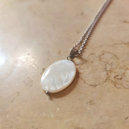 Necklace with a large shell pendant on a marble surface