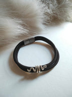 Black bracelet with a silver clasp on a white surface with fur background