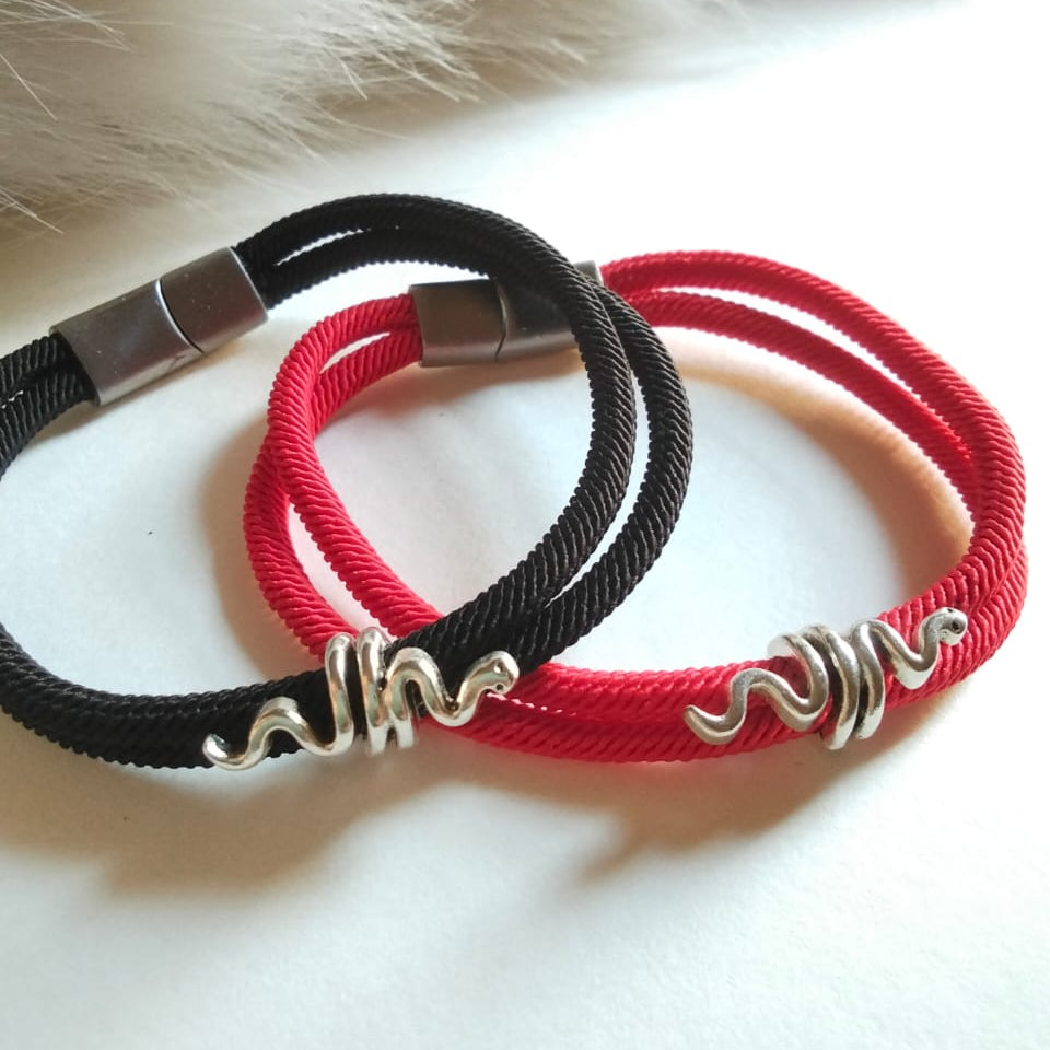 Two braided bracelets, one black and one red, with silver clasps on a fur background.