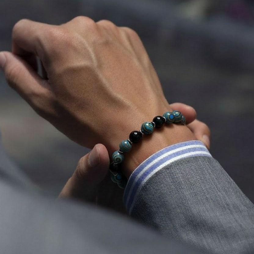 Hand wearing a beaded bracelet with a blurred background