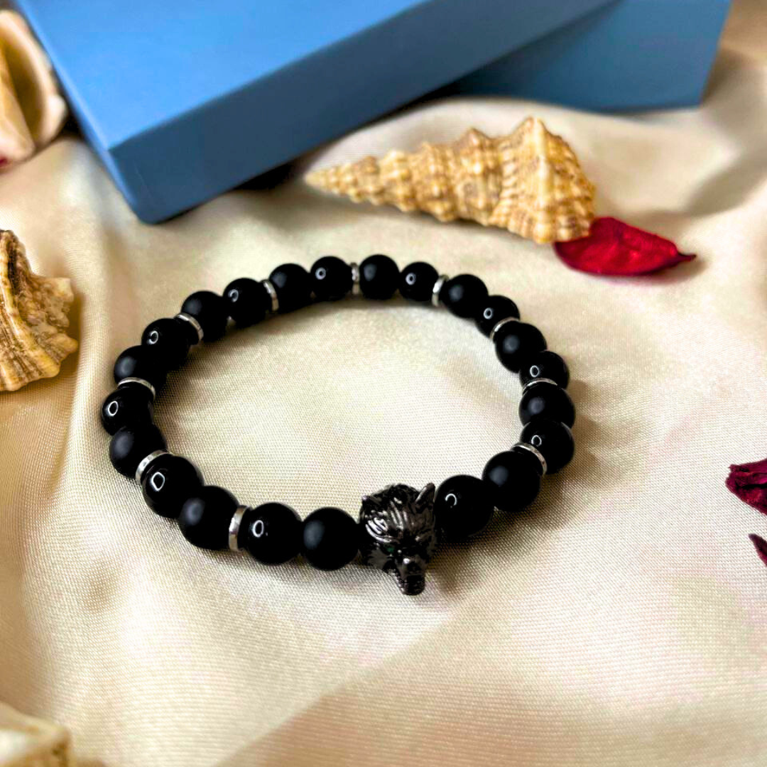 Black beaded bracelet on a beige fabric background with a blue box labeled 'YOK'.