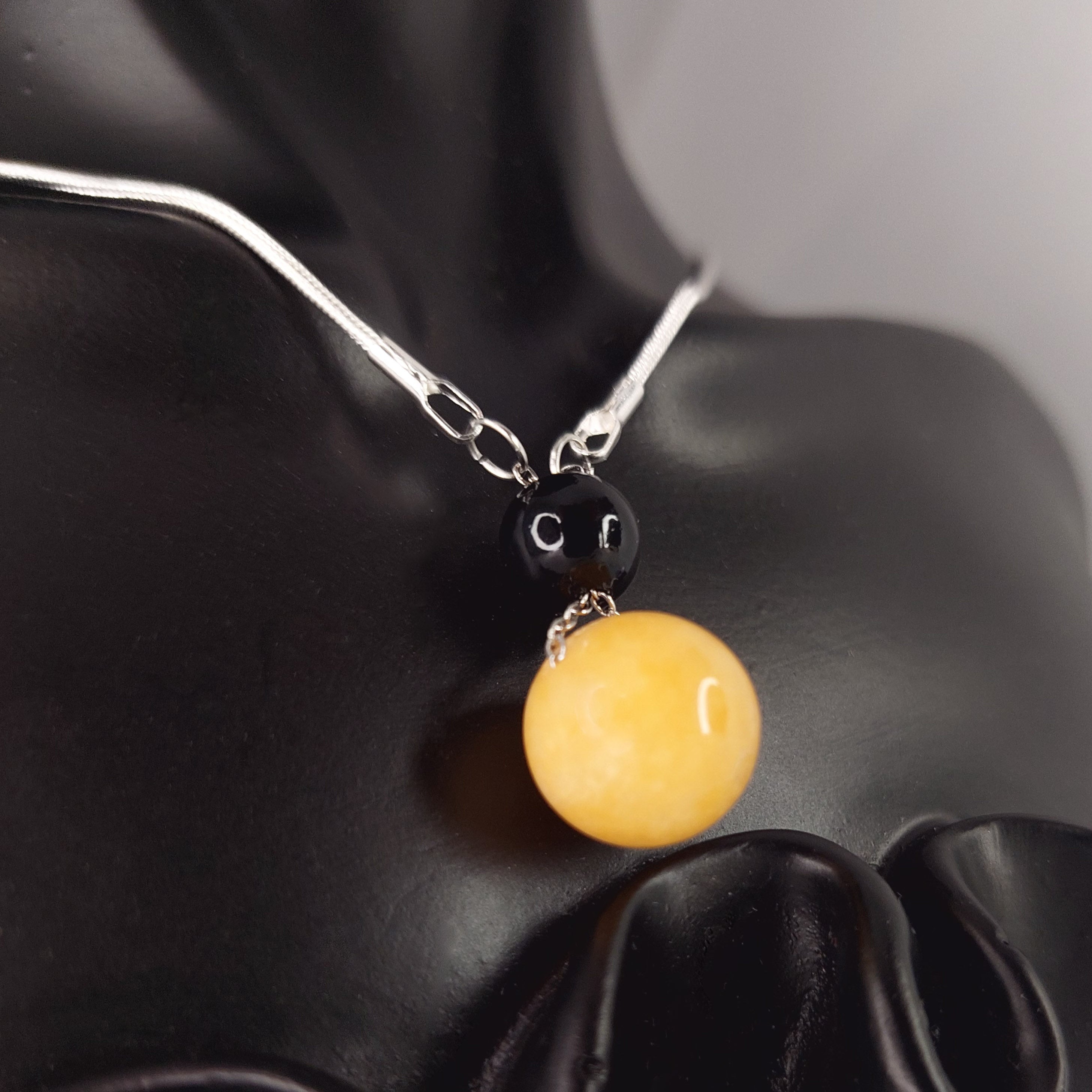 Necklace with a yellow pendant on a black fabric background

