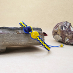 Bracelet with blue and yellow cord on a stone surface