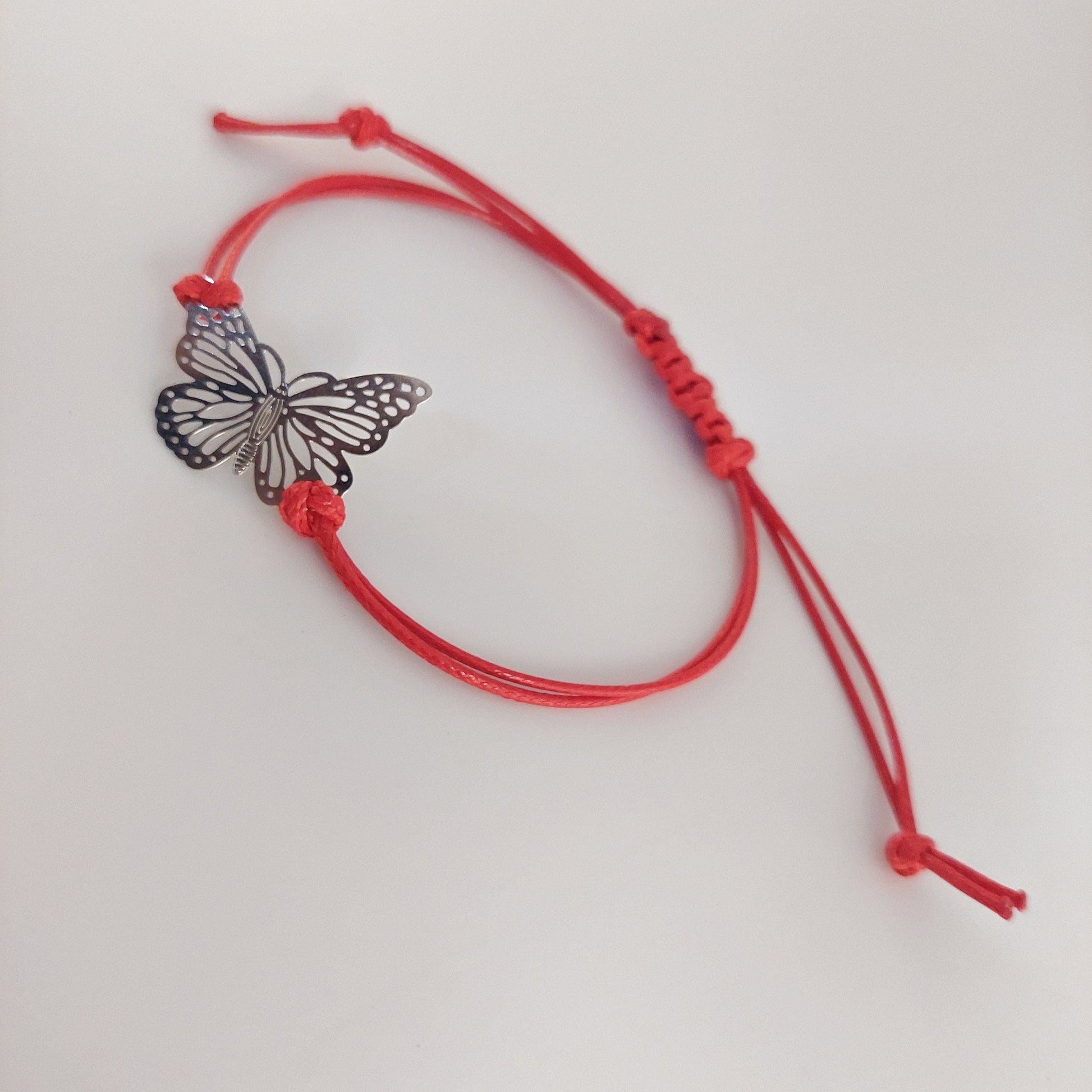 Red bracelet with a butterfly charm on a white background