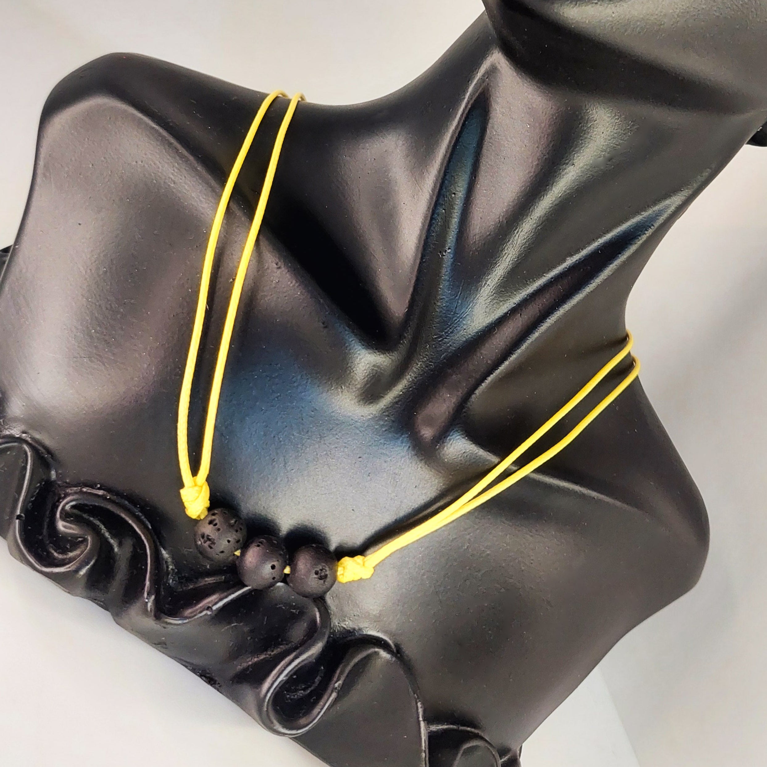 Black classical bust with yellow string on a white background