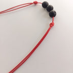 Black beaded necklace with red cord on a white background