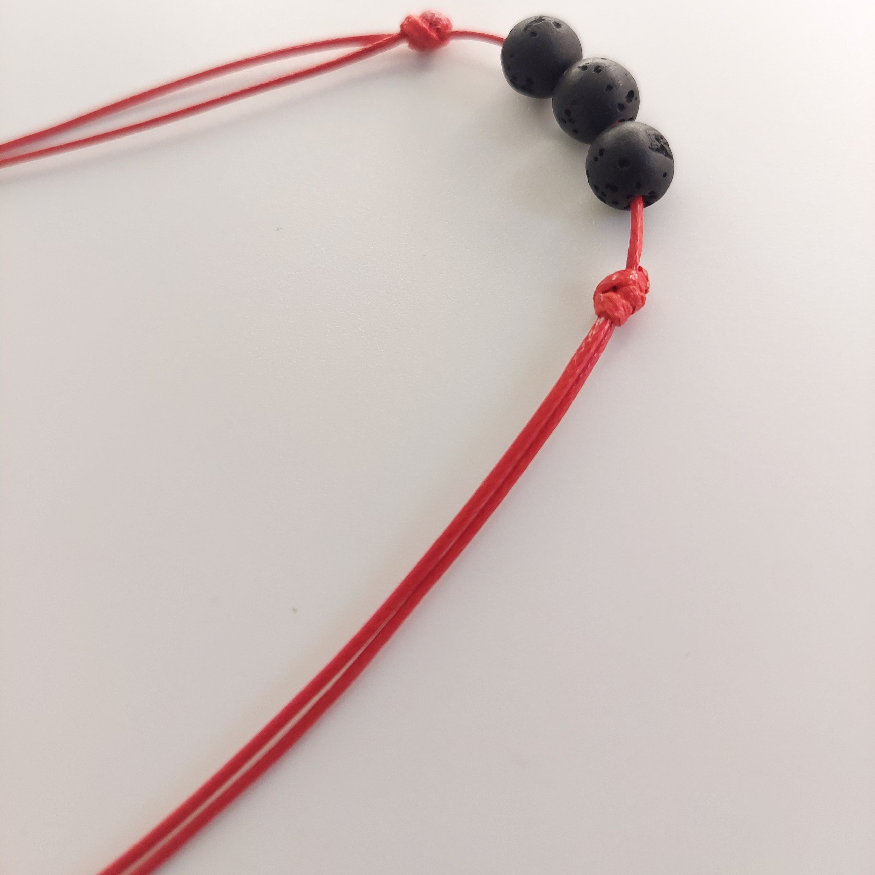 Black beaded necklace with red cord on a white background