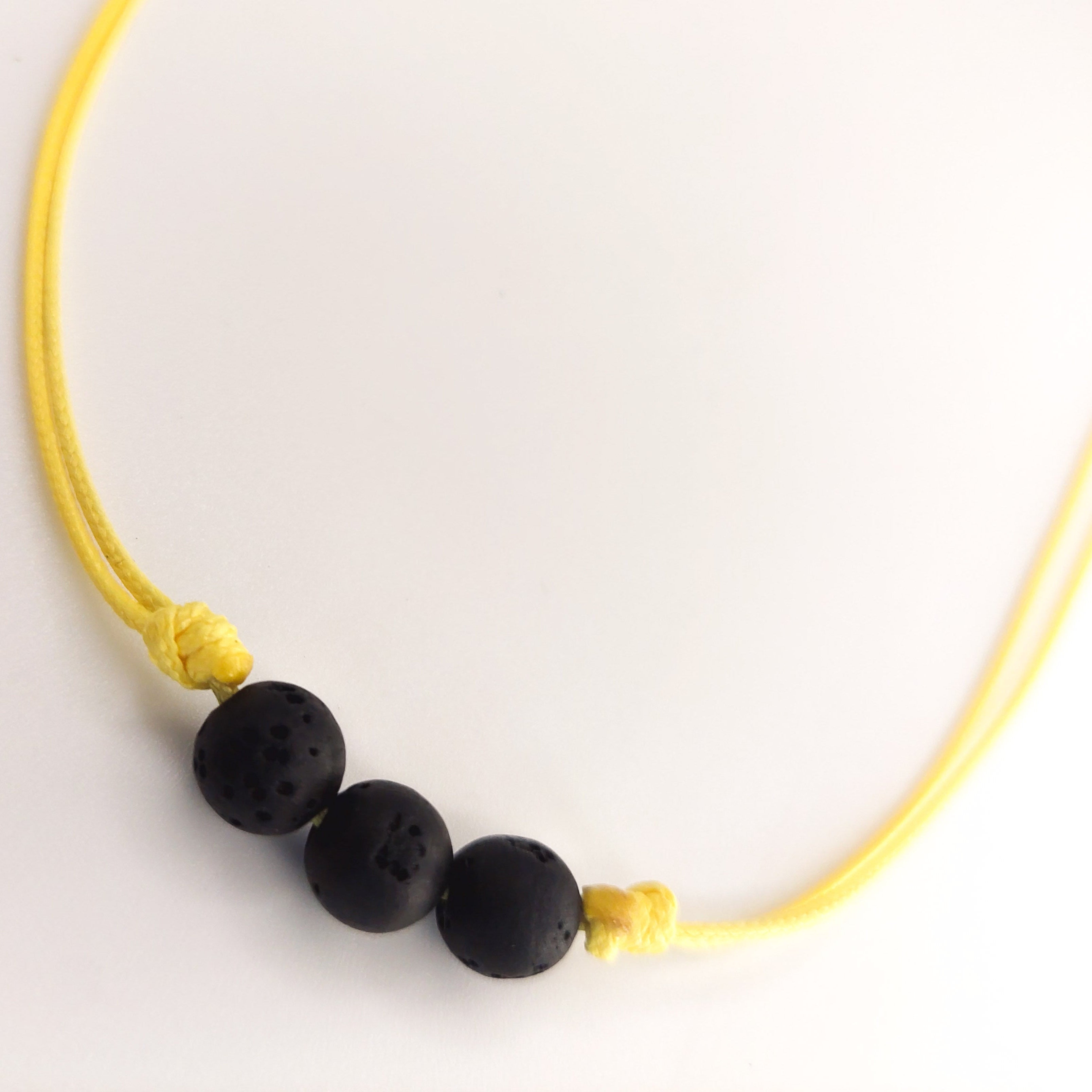 Necklace with black beads and yellow cord on a white background