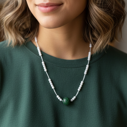 Woman wearing a green shirt and necklace with a blurred indoor background