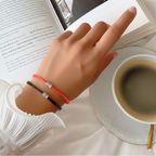 Hand with bracelets on a book and cup of coffee