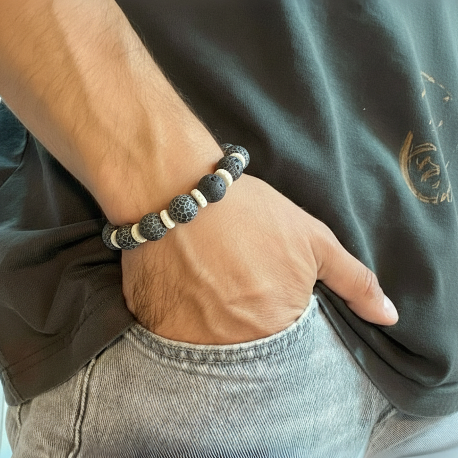 Person wearing a bracelet with dark beads and white accents on a green shirt background